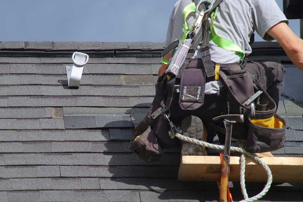 Rain falling on a residential roof above an insulated attic, with gutters carrying water away during a storm.